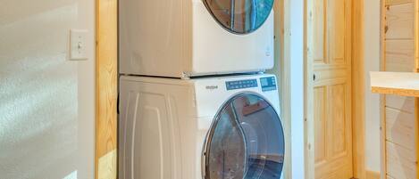 A laundry area with two stacked washers and dryers, wooden walls, and a private door.
