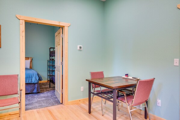 A room with a wooden table and chairs, a bed with blue bedding, and a door leading to another room. - Ultimate UP Retreat Near ATV Trails & Twin Lakes (Toivola)