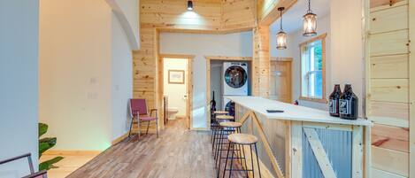 Interior de madera con una zona de bar, taburetes y una lavadora.