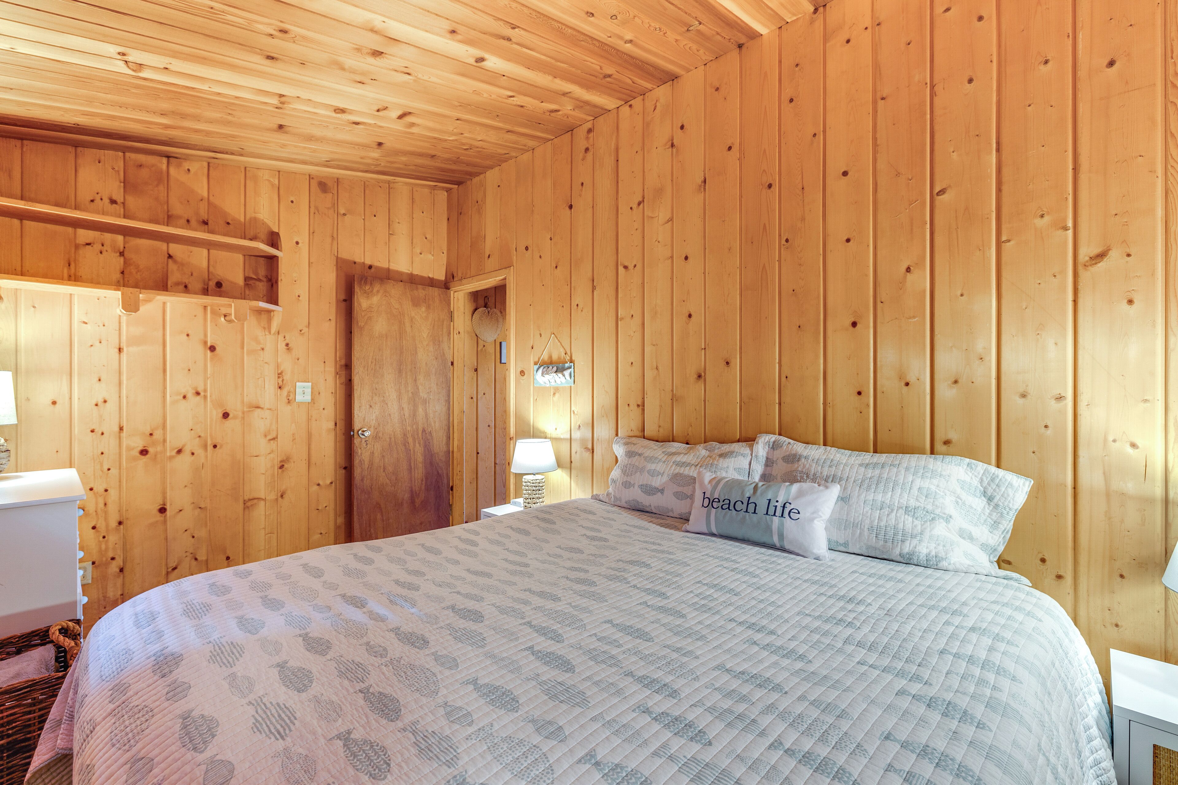A wooden-paneled room with a bed, a nightstand, and a lamp.