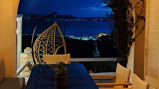 Ein gemütlicher Essbereich mit Seeblick in der Nacht, der einen Tisch, Stühle und einen dekorativen Bogen mit Pflanzen zeigt.