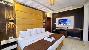 A hotel room with a large bed, a desk, a TV, and a wardrobe. - Presken White House Micheal Olawale (Lekki)
