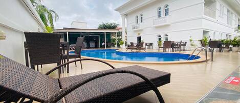 A poolside area with lounge chairs and a pool.