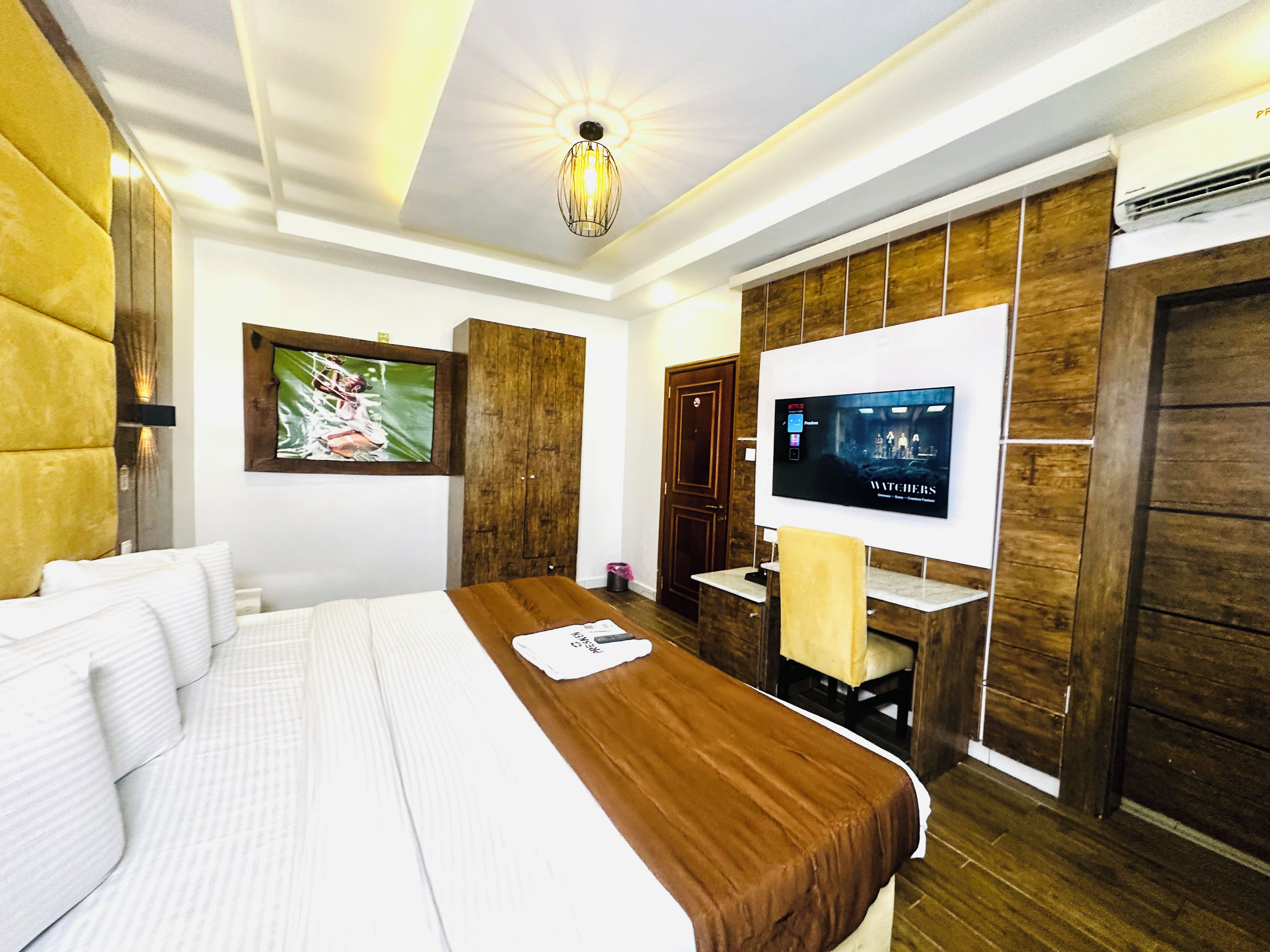 A hotel room with a large bed, a television mounted on the wall, and a wooden wardrobe.