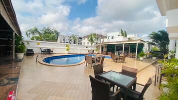 Un área de piscina en la azotea con una piscina circular, mobiliario exterior y plantas en macetas.