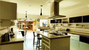 A modern kitchen with a central island, built-in appliances, and a dining area with bar stools. - Villa Amarela (Búzios)