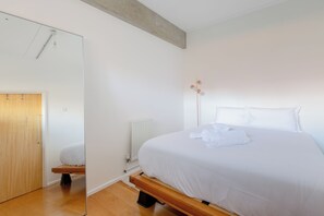 Une chambre à coucher avec un lit, un banc en bois, un radiateur et un miroir.