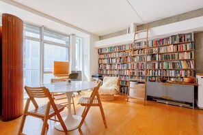 Eine großzügige Bibliothek mit vielen Bücherregalen, einem runden Tisch mit Stühlen und einem modernen Design.