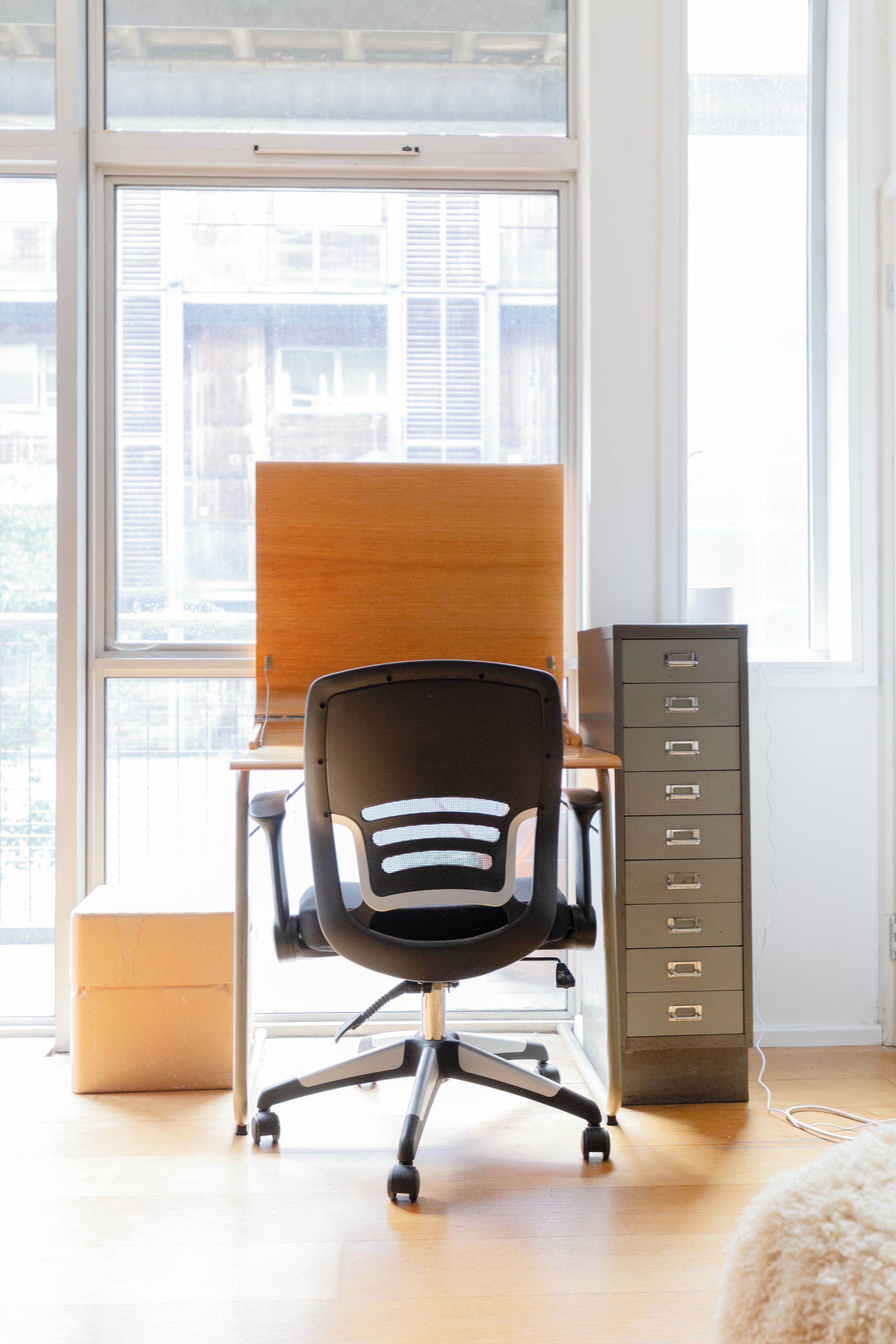 A workspace with a black office chair, a wooden desk, and a filing cabinet.
