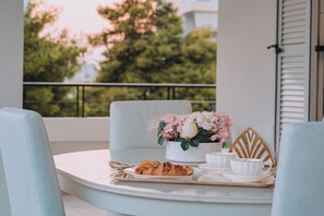 A balcony with a table set for breakfast, including croissants, cups, and a floral arrangement. - Luxurious Stylish 2 Bd Villa in Voula (Vari-Voula-Vouliagmeni)