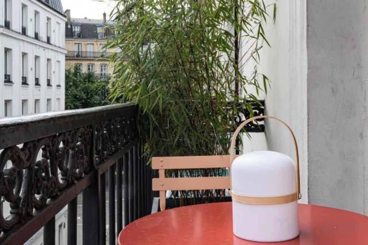A white cylindrical object with a handle on a red table, a wooden chair, and a black metal railing.