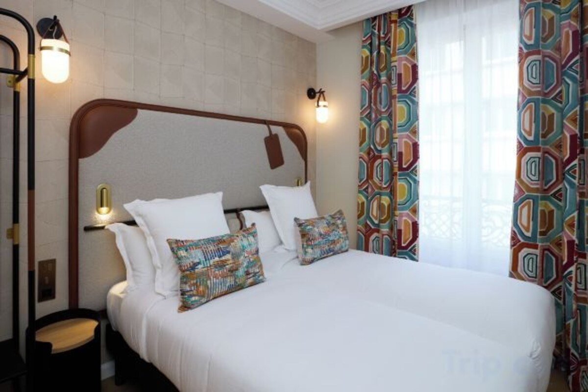 A hotel room with a large bed, a nightstand, and a mirror.