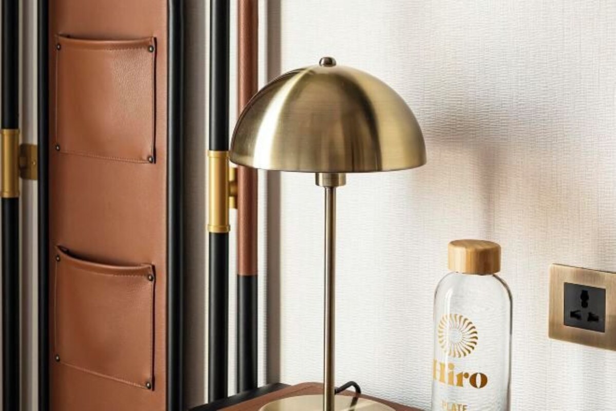 Ein Zimmer mit einer Messinglampe, einer Spirituosenflasche und einer Tür mit Lederverkleidungen.