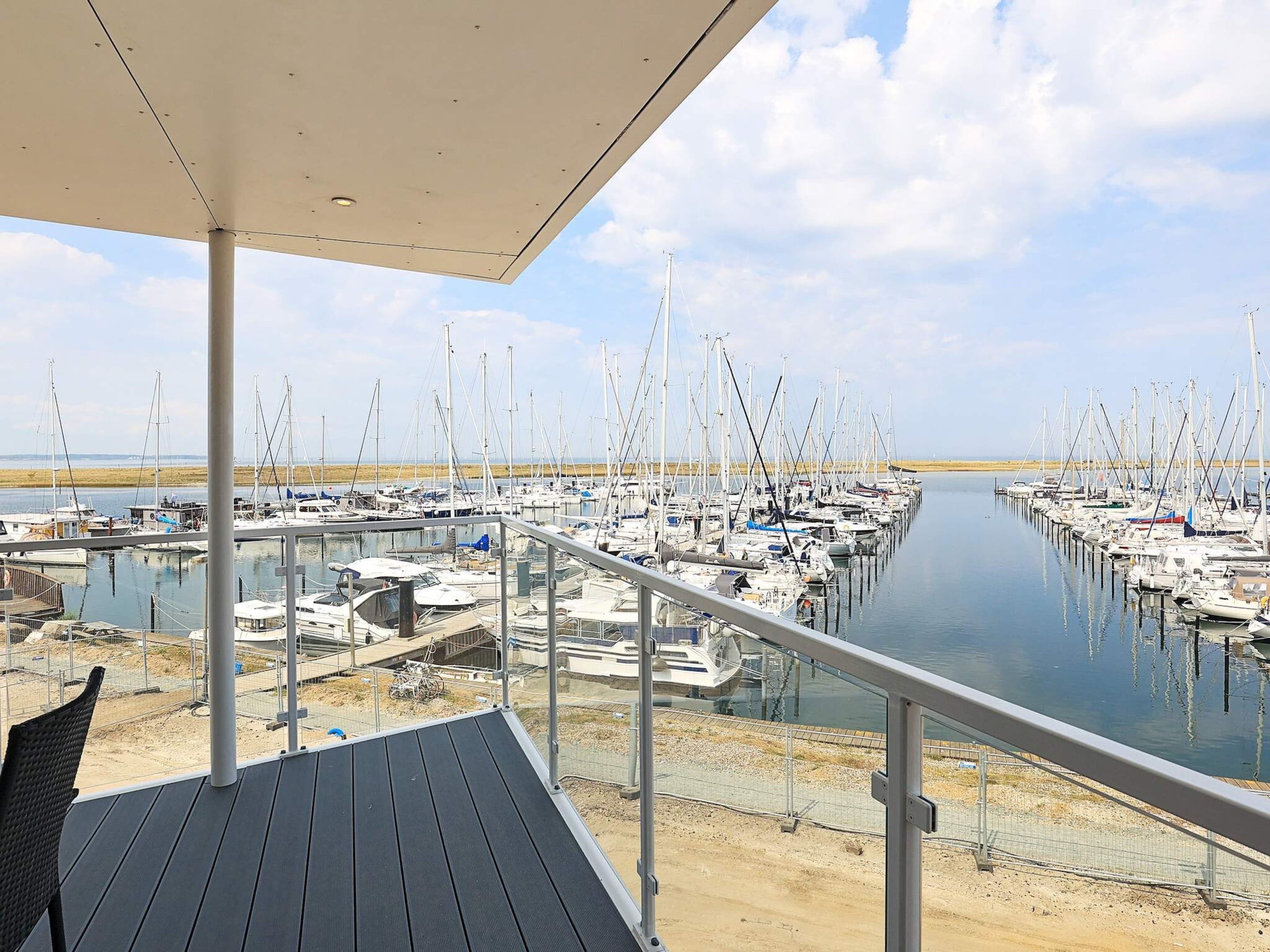 Una marina con barcos amarrados en aguas tranquilas, una zona de cubierta techada y cielo despejado.