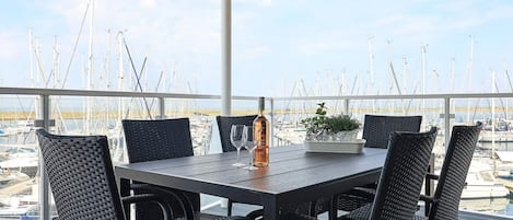 A terrace with a table and chairs, overlooking a marina with numerous boats.