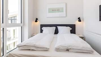 A hotel room with a bed, two bedside tables, a wall-mounted light, and a window.