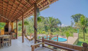 A covered outdoor area with a pool, wooden furniture, and a hammock. - Casa em Paraty com Piscina e Churrasqueira (Paraty)