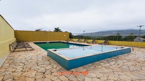 Et rektangulært swimmingpool med belægning af sten, omgivet af en gul mur og et hegn.