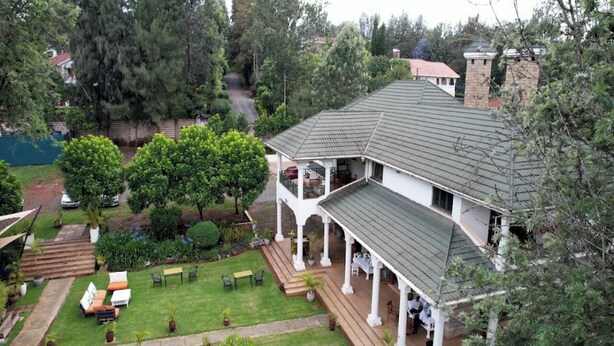A large house with a covered porch and a well-maintained lawn. - The Palace Inn Karen (Nairobi)
