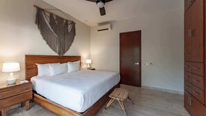 Un dormitorio con cama de madera, lámparas de noche, ventilador de techo, un colgador de macramé y un armario.