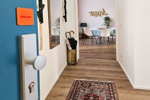 A hallway with a blue door, a brass radiator, a patterned rug, and a dining area with a table and chairs. - Red Orange Palm - 200m2 - stylish, original, central  (Vienna)