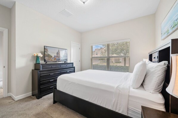 Een slaapkamer met een bed, een dressoir en een raam met jaloezieën.