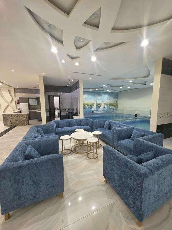 Uma área de convívio moderna com sofás azuis, piscina e um mural de um veleiro.