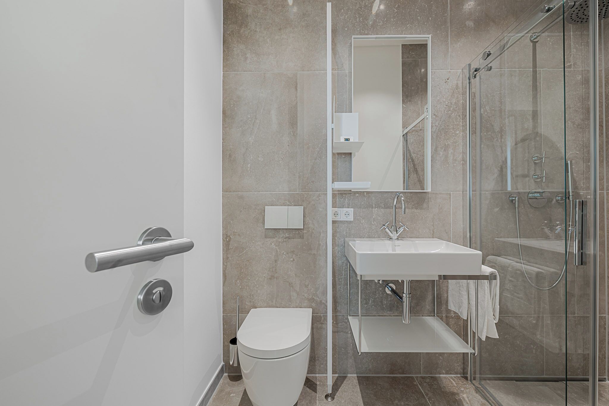 Ein modernes Badezimmer mit Toilette, Waschbecken und Duschkabine aus Glas.