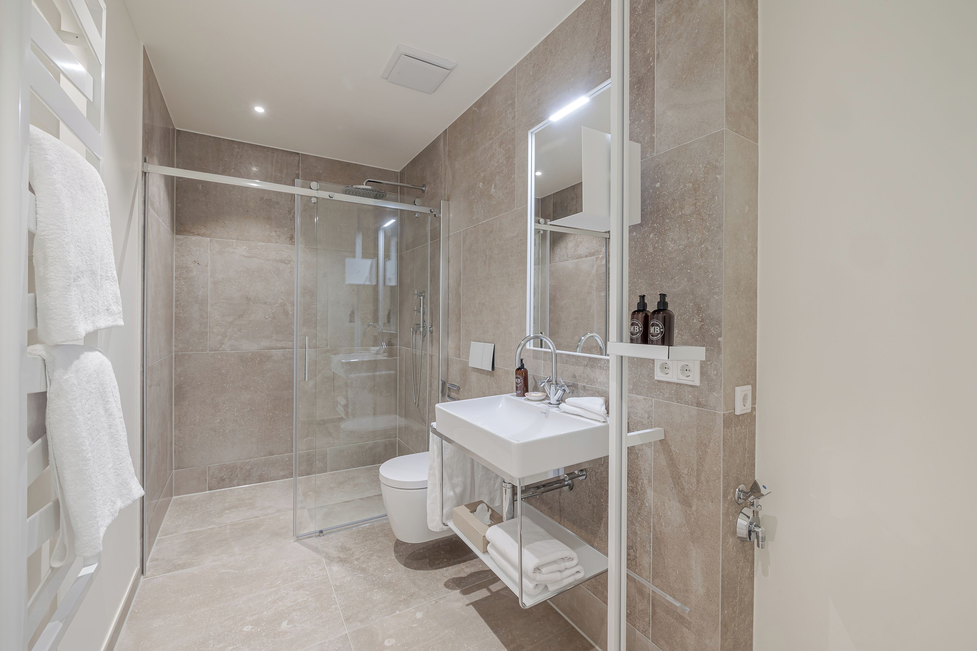 A modern bathroom with a glass-enclosed shower, a white sink, and a mirror above it.