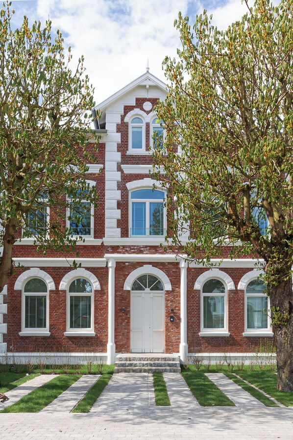 A two-story brick building with a central entrance, arched windows, and a symmetrical facade. - Apartments Hotel Stadt Hamburg (Sylt)