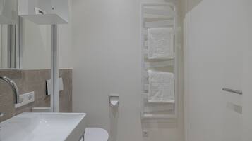 A modern bathroom with a white sink, toilet, and towel rack.