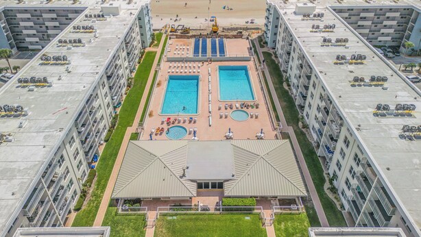 Un hotel de gran altura con dos piscinas, una terraza en la azotea y vista al mar.