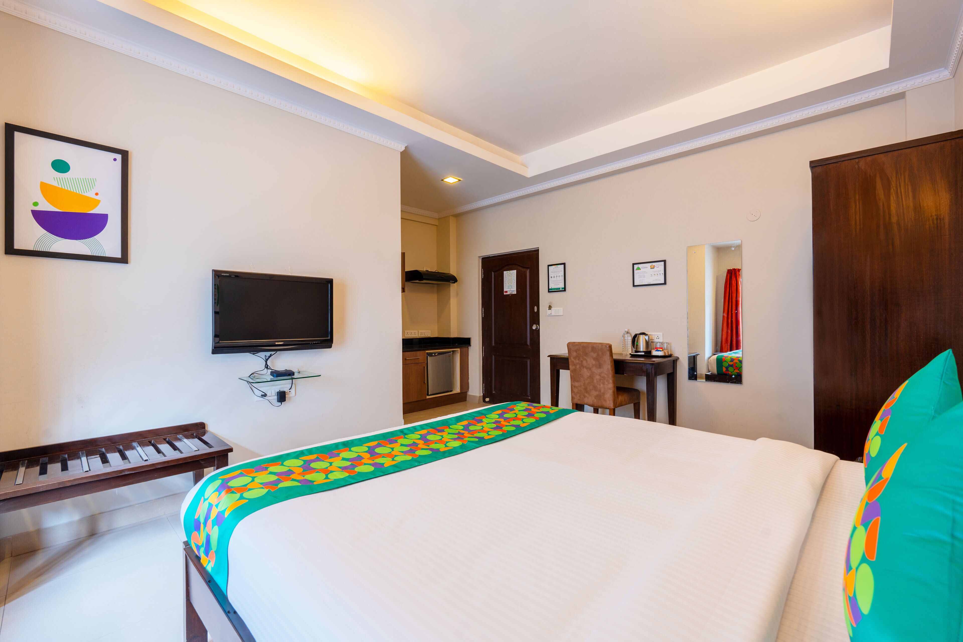 Ein Hotelzimmer mit Bett, Fernseher, Klavier, Schreibtisch und einem durch eine geöffnete Tür einsehbaren Badezimmer.