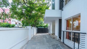 A narrow, paved pathway leading to a modern building with a white exterior and large windows. - Treebo Ivory White Inn (Bengaluru)