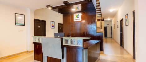 A reception desk with a logo, a staircase, and a hallway with doors.