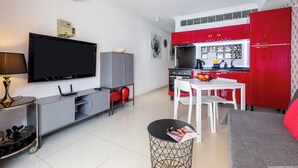Una cocina moderna con armarios rojos, un televisor de pantalla plana y un comedor con mesa y sillas.