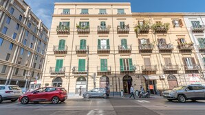 Un edificio de varios pisos con balcones, una tienda y un paso de peatones.
