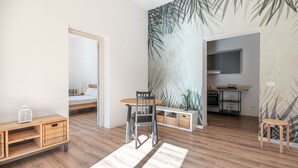 Una habitación moderna con piso de madera, comedor con mesa y sillas, kitchenette y cama con vista.