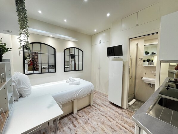 Cozy retreat with a neatly made bed, desk, and large mirror, perfect for relaxation and work.