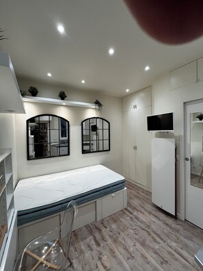 Relax in this serene bedroom with a large bed, two framed mirrors, and a flat-screen TV.