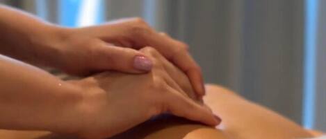 Nahaufnahme von Händen, die eine Rückenmassage geben.