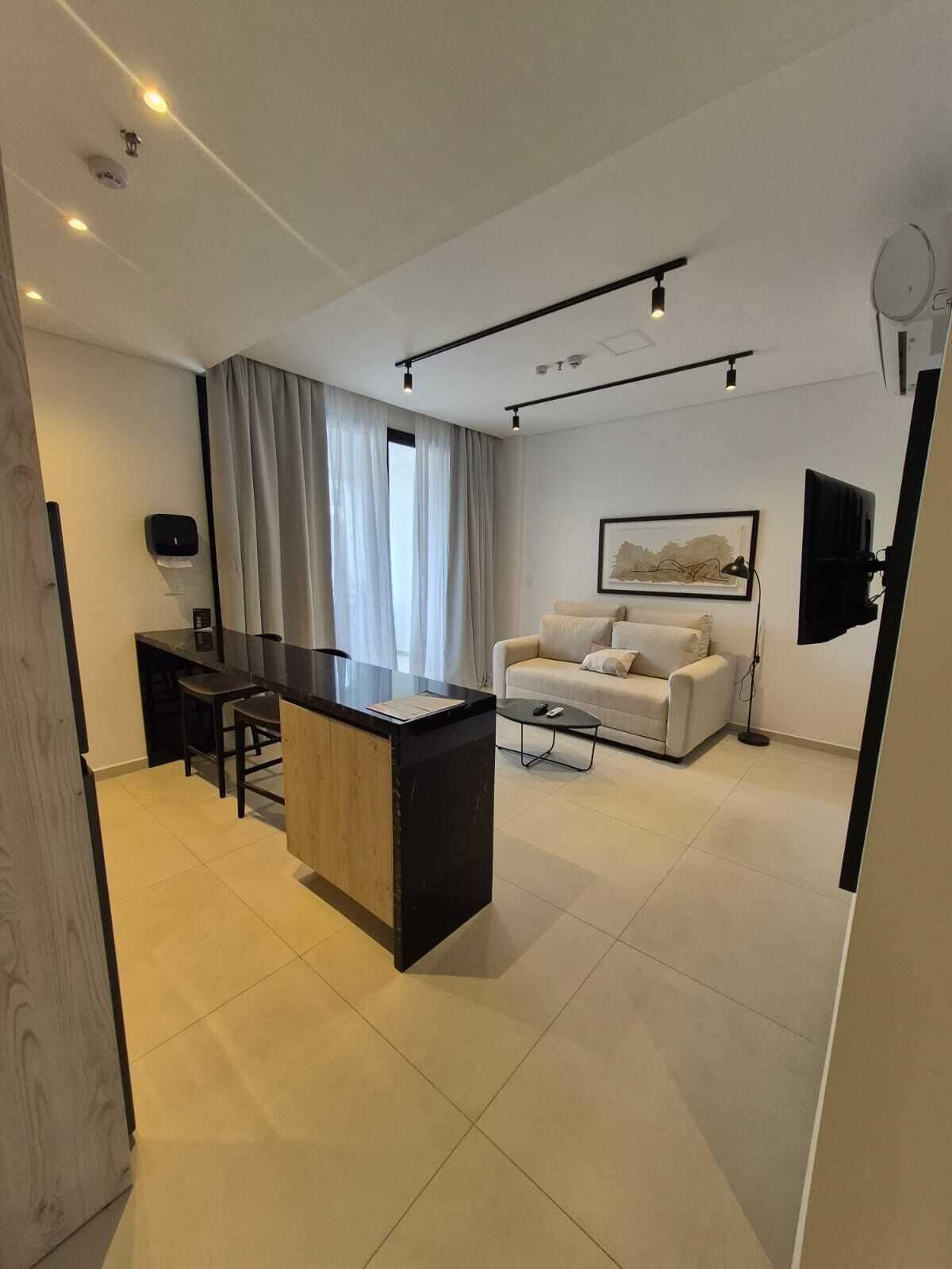 A modern living room with a sofa, a coffee table, and a desk with a computer.