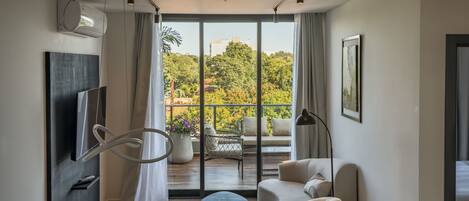 Una sala de estar moderna con comedor, ventanas grandes y vistas a zonas verdes.