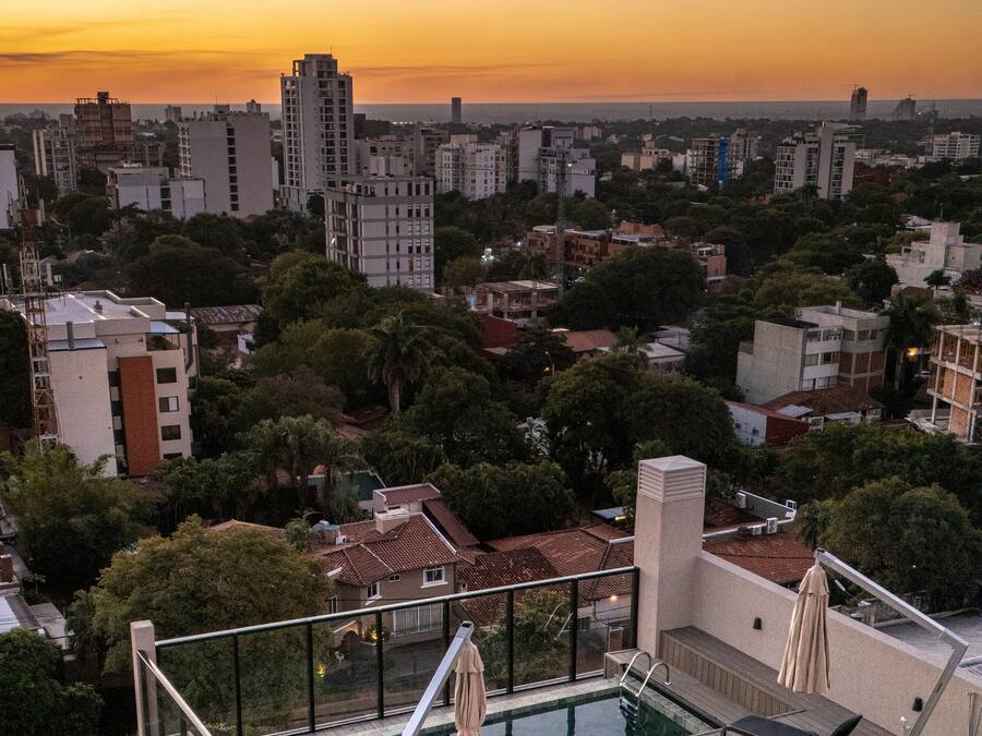 A rooftop pool area with a view of the cityscape during sunset.