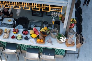 Un bar proposant une variété de fruits et d’en-cas, une fontaine à boissons et un espace détente avec des chaises.