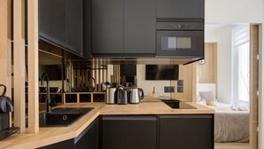 A modern kitchen with black cabinets, a wooden countertop, a built-in oven, and a large window. - 343 Michau - Cozy apartment near Sacré-Coeur (Paris 18 Buttes-Montmartre)