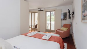 Une chambre d’hôtel avec un lit, une chaise, un bureau et un balcon.