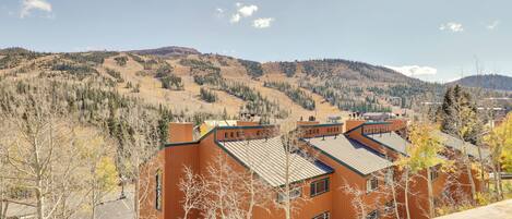 A building with a red exterior and a sloped roof, surrounded by trees and a mountainous landscape.