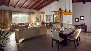 Un vaste salon doté d’un haut plafond, un coin repas avec une table et des chaises en bois, et un espace salon confortable avec des canapés et une table basse.