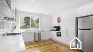 A modern kitchen with white cabinetry, stainless steel appliances, and a wooden floor. - Banksia Beach Retreat *1 NIGHT FREE* (Blairgowrie)